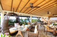 Un restaurante con mesas y sillas y un ventilador de techo. en Cape Panwa Hotel Phuket, en Panwa Beach