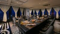 un restaurante con mesas largas, sillas y cortinas en La Sinfonía Citadel Hotel and Spa, en Hanói