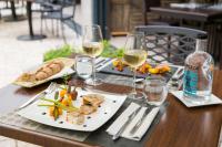 Una mesa con un plato de comida y dos copas de vino. en Hôtel & Spa du Domaine des Thômeaux, The Originals Relais, en Mosnes