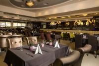 Un restaurante con mesas y sillas y un bar. en Duna Garden Hotel, en Budapest