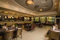 Un restaurante con mesas y sillas y un bar. en Duna Garden Hotel, en Budapest