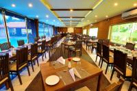 een restaurant met houten tafels en stoelen en ramen bij Jal Mahal Resort and Spa in Mysore