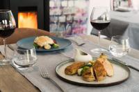 a table with two plates of food and wine glasses at La Ferme Blanche, The Originals Relais in Lompret