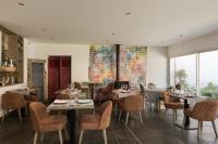 a dining room with tables and chairs and windows at La Ferme Blanche, The Originals Relais in Lompret
