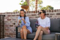 two women sitting on a couch with drinks at BIG4 Sandstone Point Holiday Resort Bribie Island in Bongaree