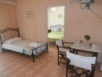 a room with a bed and a table and chairs at Pansion Porto Tsi Ostrias in Keri