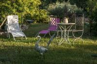 a peacock standing in the grass next to a table and chairs at Chambres d&#39;Hôtes de Curnier in Bédoin
