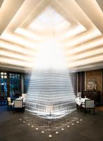 a large glass fountain in a restaurant with tables and chairs at Jaya House River Park Hotel in Siem Reap