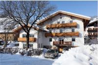 a building with a car parked in the snow at Pension Rosenhof in Brixen im Thale