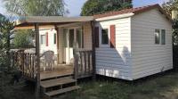 une petite maison blanche avec une terrasse couverte et une chaise dans l&#39;établissement Camping La Prairie, au Muy
