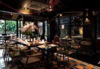 バンコクにあるDhevi Bangkok Hotelのダイニングルーム(テーブル、椅子、花付)