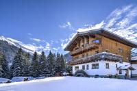 a large wooden building with snow on the ground at Pension Sattelkopf in Sankt Anton am Arlberg