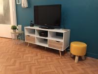 a white entertainment center with a tv and a stool at Appartement Le Grand Parc in Châteauroux