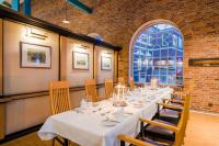 a dining room with a long table with chairs and a window at Hotel Alte Werft in Papenburg