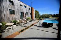a swimming pool with tables and chairs next to a building at Le sentier des étangs in Barsy