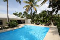 a swimming pool in front of a house with palm trees at Villa Les Palmiers in Saint-François