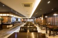 Un restaurante con mesas y sillas de madera y una cafetería. en Vistacay Hotel Worldcup, en Seogwipo