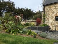 a garden with plants and a stone building at Kervran in Plouhinec