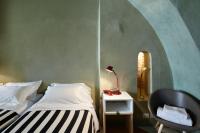 a bedroom with two beds and a chair at Palazzetto Rosso - Art Hotel in Siena
