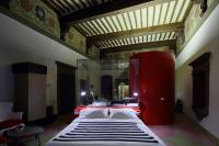 a bedroom with a large red bed with a mirror at Palazzetto Rosso - Art Hotel in Siena