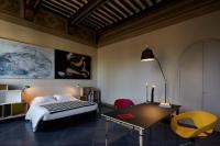 a bedroom with a bed and a desk and a table at Palazzetto Rosso - Art Hotel in Siena
