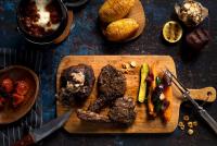 een snijplank met vlees en groenten op een tafel bij Kambaku River Lodge in Malelane