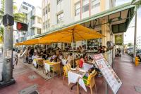 a group of people sitting at a restaurant under an umbrella at Majestic Hotel South Beach in Miami Beach