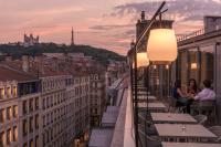 people sitting on a balcony overlooking the city at sunset at Maison Nô - Hôtel et Rooftop in Lyon