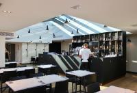 a man standing behind a bar in a restaurant at Maison Nô - Hôtel et Rooftop in Lyon