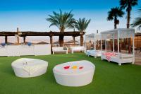 2 weiße Betten auf einem Rasen mit Palmen in der Unterkunft U Coral Beach Club Eilat – Ultra All inclusive in Eilat