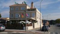 a building with flags in front of it on a street at Hotel Las Canteras de Puerto Real in Puerto Real