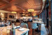 希洛谢克A-ROSA Ifen Hotel Kleinwalsertal的一家有着木质天花板、桌椅的餐厅