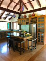 a kitchen with wooden cabinets and a large island with stools at Koh Jum Beach Villas "A member of Secret Retreats" in Ko Jum