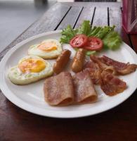 une assiette de petit-déjeuner avec des œufs, du bacon, des tomates et de la laitue dans l'établissement Baan Sabaijai Resort, à That Phanom