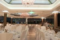 um salão de banquetes com mesas e cadeiras brancas e um lustre em The Athenian Callirhoe Exclusive Hotel em Atenas
