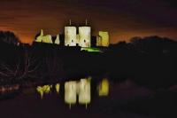 a castle at night with its reflection in the water at Garden Suite in Rhuddlan