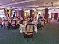 a group of people sitting at tables in a restaurant at Magus Hotel in Baia Mare