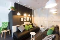 Una sala de estar con un sofá marrón y almohadas verdes. en Song Hotel Sydney, en Sídney