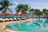 a swimming pool with chairs and umbrellas and the ocean at Amari Phuket in Patong Beach