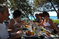 een groep mensen die aan een tafel zitten en eten bij Hotel Le Ruesco in Olmeto