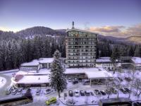 Un gran edificio con nieve en el suelo en un estacionamiento. en Grand Hotel Murgavets, en Pamporovo
