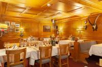 ein Restaurant mit weißen Tischen und Stühlen sowie Holzwänden in der Unterkunft Hotel Jägerhof in Zermatt