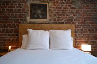 a bed with white pillows in front of a brick wall at Chambre d&#39;hôtes la Teinturerie in Roubaix