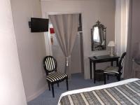 a bedroom with a bed and a desk and chairs at Hôtel De Londres in Boulogne-sur-Mer
