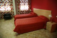 Dos camas en una habitación de hotel con paredes rojas. en HOSTAL EL POLIGONO, en La Roda