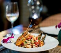 Haad Chao PhaoBeyond The Blue Horizon Boutique Bungalows的桌上的一小块食物,加上一杯葡萄酒