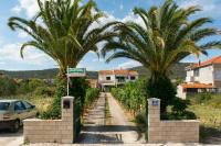 a driveway with palm trees and a house at Apartmani Stjepan in Vinišće