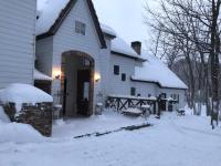 una casa blanca con nieve en el suelo en Petit Hotel Kurumi to Milk, en Tateshina