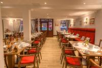 a restaurant with wooden tables and chairs and red booths at Hotel Zum Bär in Quedlinburg