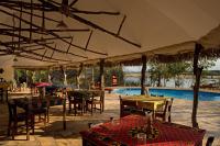 a restaurant with tables and chairs and a swimming pool at Selous River Camp in Kwangwazi